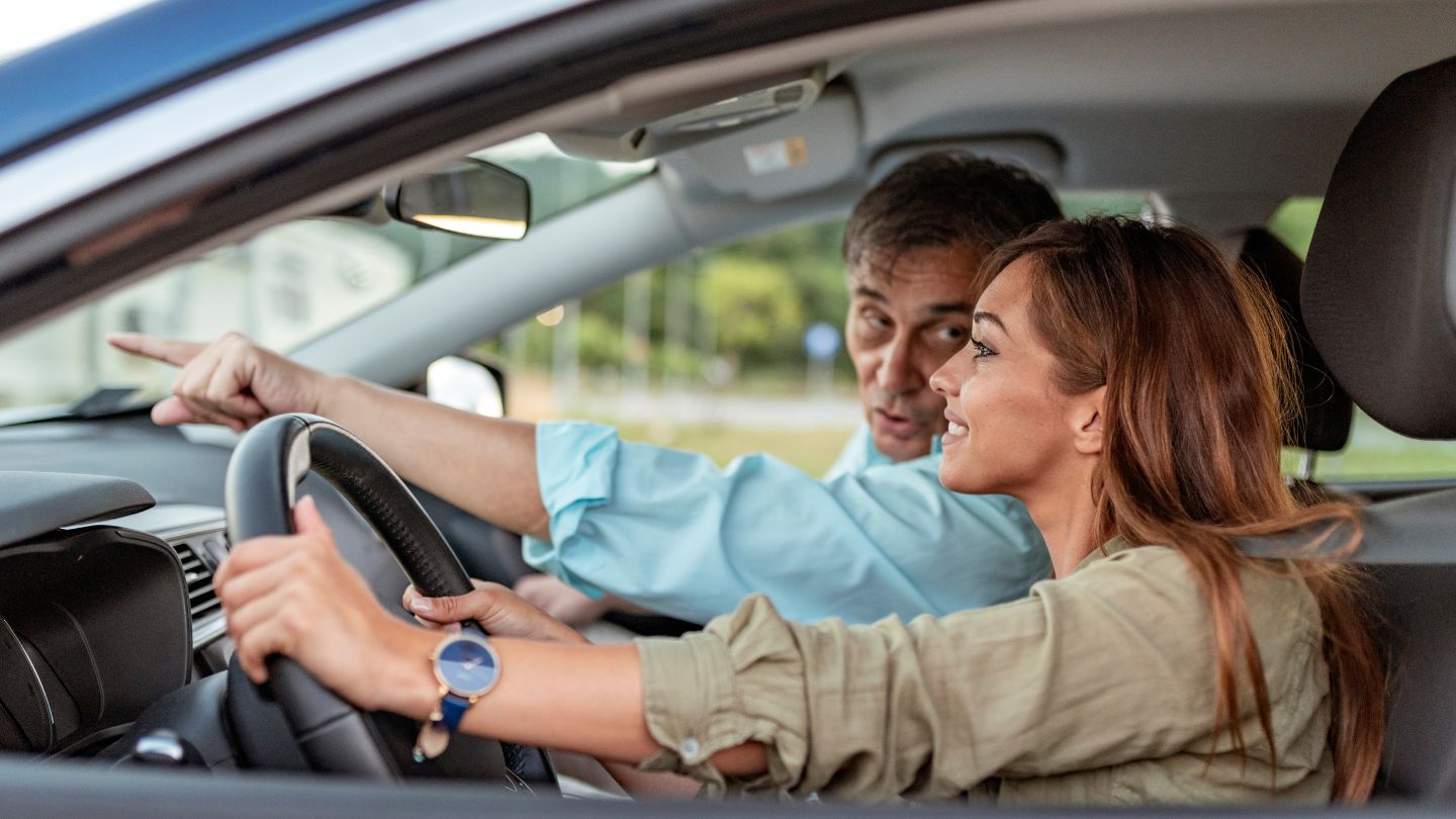 Driving Instructor Guiding A Learner Behind The Wheel 