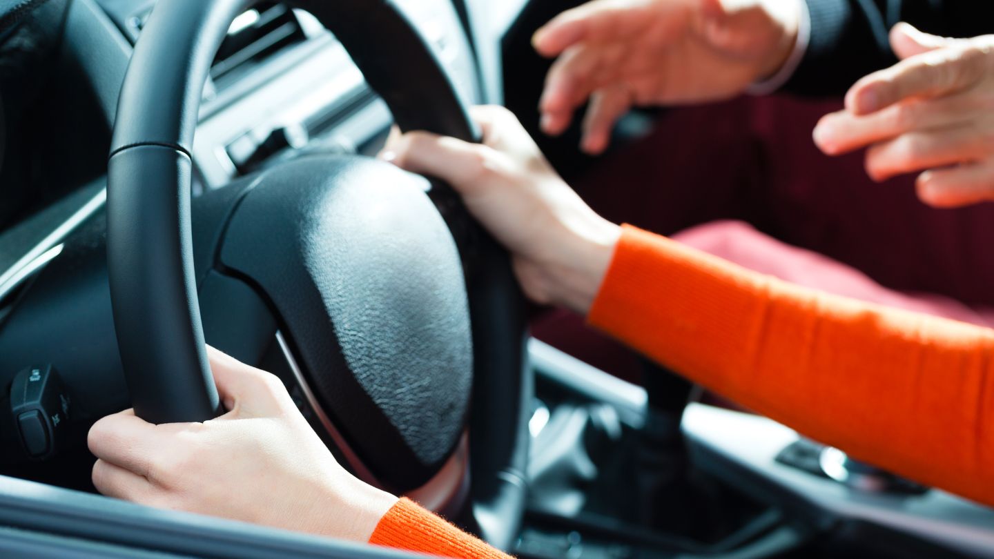 Person Gripping Steering Wheel with Instructor