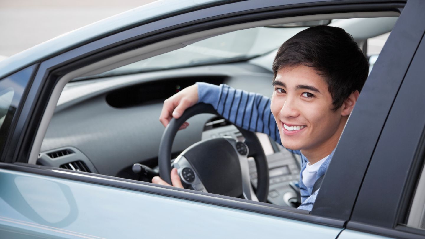 Teenager Sitting in Car and Smiling