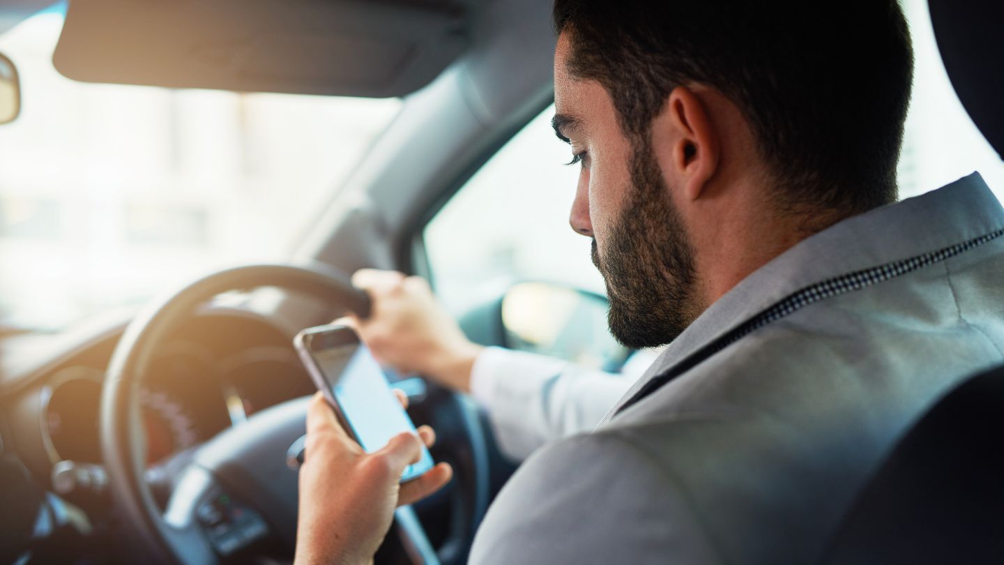 Driver Checking Phone While Behind The Wheel 