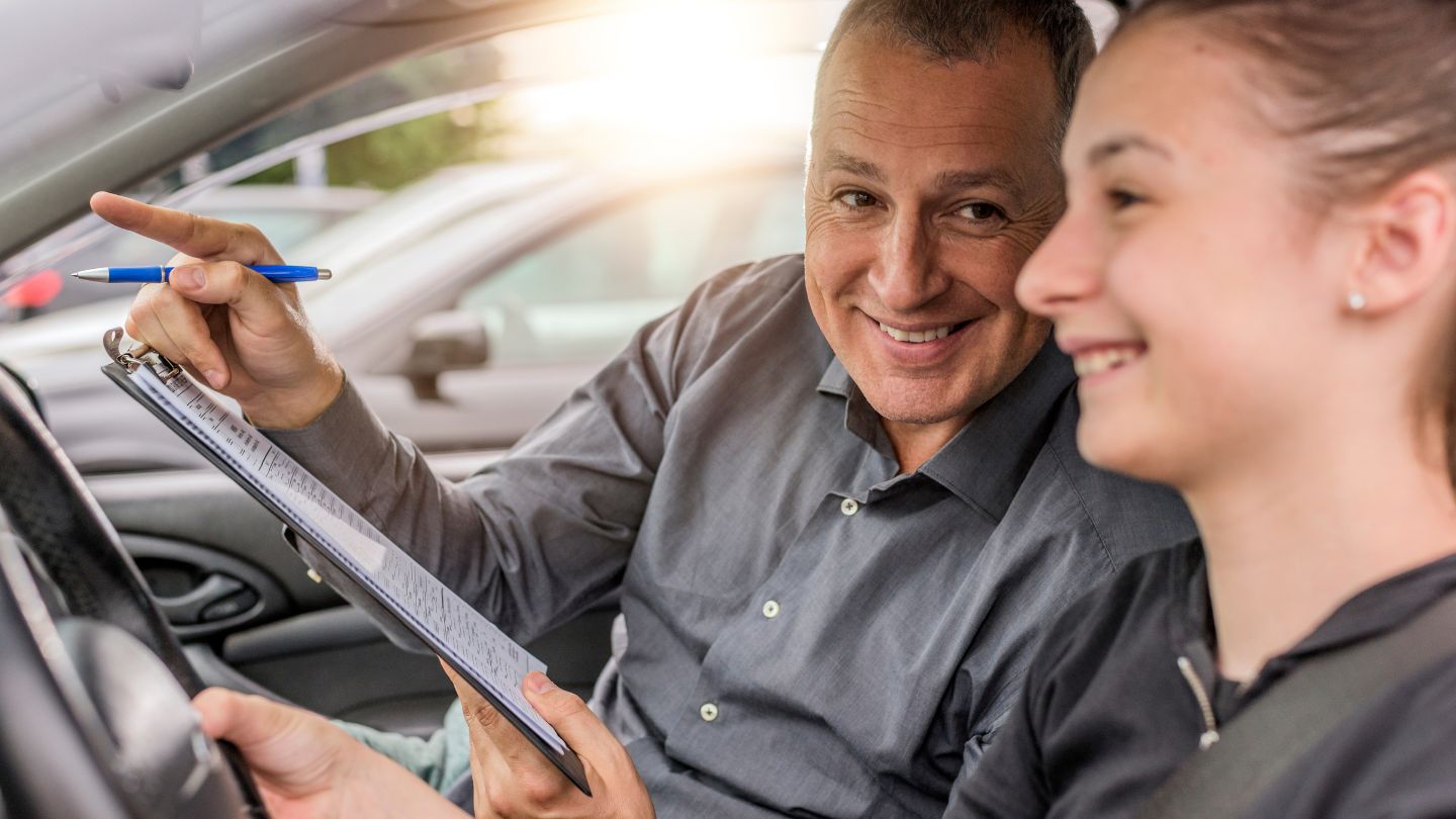 Driving Instructor Guiding A Smiling Student 