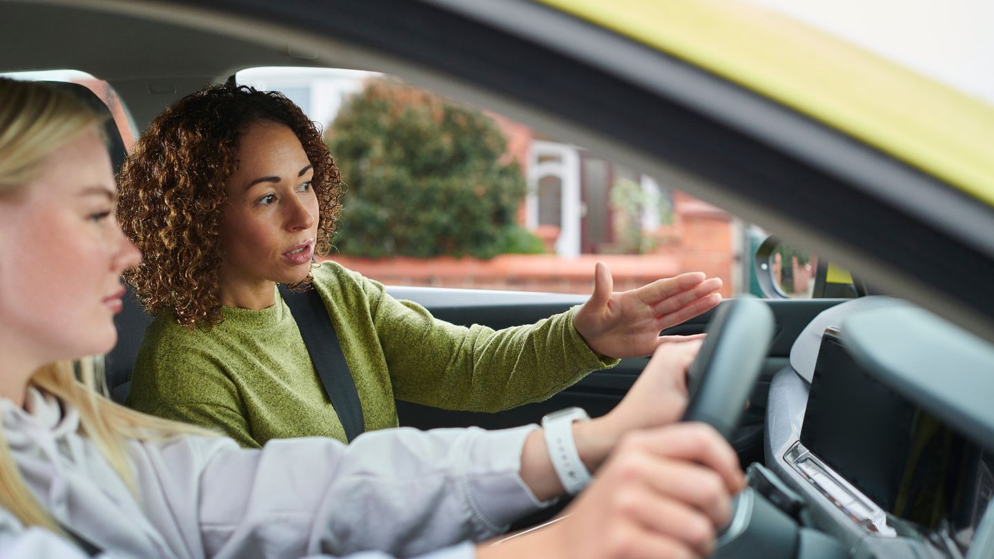 Driving Instructor Guiding A Student Driver 